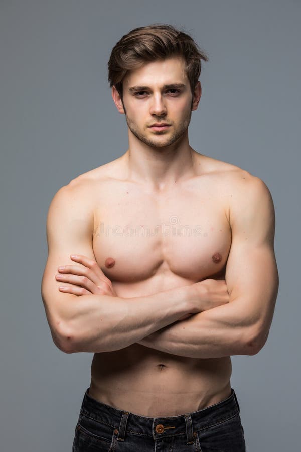 Hombre muscular del culturista del atleta con un torso desnudo en un fondo gris fotos de archivo libres de regalías Hombre muscular del culturista del atleta con un torso desnudo en un fondo gris fotos de archivo libres de regalías