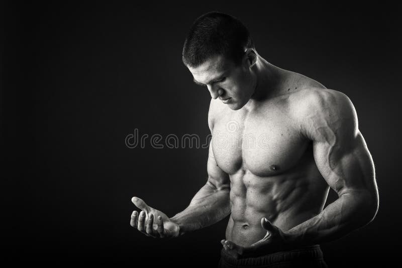 Hombre muscular en un fondo oscuro imagen de archivo Hombre muscular en un fondo oscuro imagen de archivo