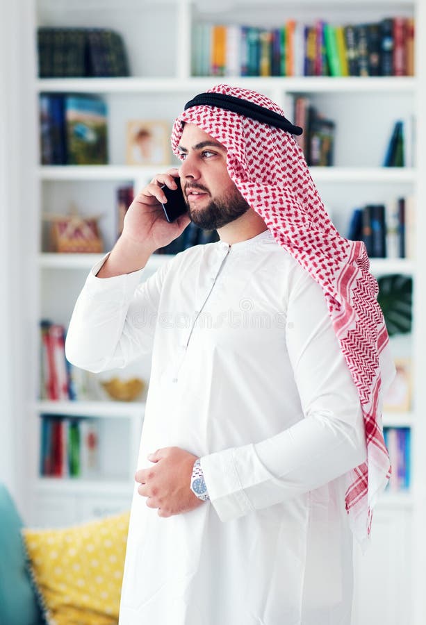 Hombre musulmán adulto joven que habla en el teléfono en casa foto de archivo Hombre musulmán adulto joven que habla en el teléfono en casa foto de archivo