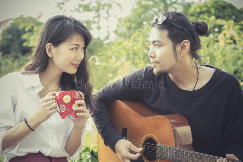 Asian younger men and women playing guitar with happiness emotion. Asian younger men and women playing guitar with happiness emotion