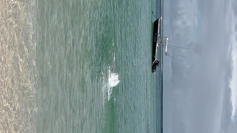 Hombre nadando hacia un bote flotando en el mar contra el cielo