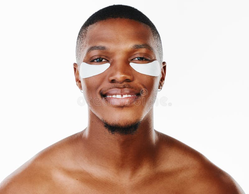 Hombre negro ardiente y retrato con parches cosméticos para hidratación en la higiene dermatológica sobre fondo blanco. masculino fotografía de archivo libre de regalías