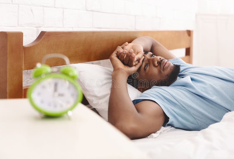 Sleep disorder. Young african-american guy in bed suffering from insomnia, thinking about his problems at night, copy space. Sleep disorder. Young african-american guy in bed suffering from insomnia, thinking about his problems at night, copy space