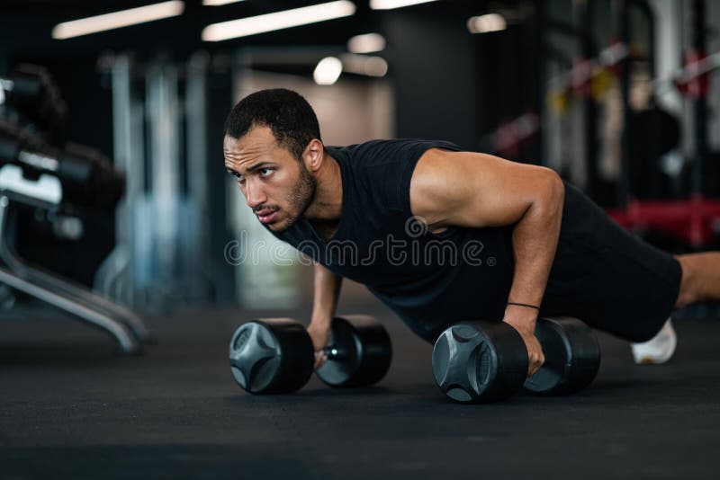 Hombre musculoso atlético en auriculares inalámbricos escuchando música  durante el entrenamiento en el gimnasio