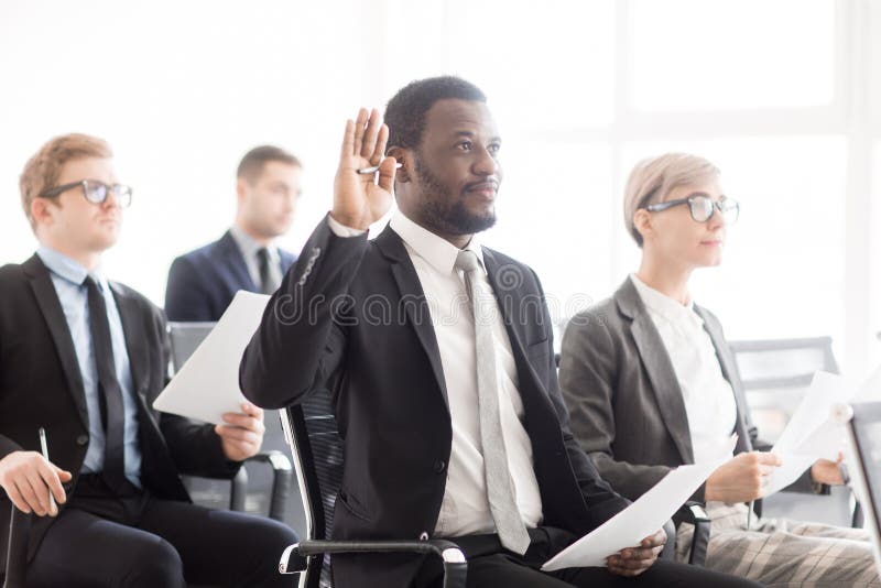 Hombre negro que aumenta la mano en la reunión de negocios imagen de archivo libre de regalías Hombre negro que aumenta la mano en la reunión de negocios imagen de archivo libre de regalías