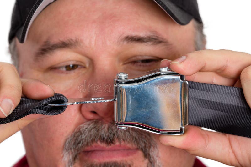 Stupid dim-witted man unable to fasten a seatbelt or perform the most simple task holding the buckle and clip in front of his face as he tries to solve the problem. Stupid dim-witted man unable to fasten a seatbelt or perform the most simple task holding the buckle and clip in front of his face as he tries to solve the problem