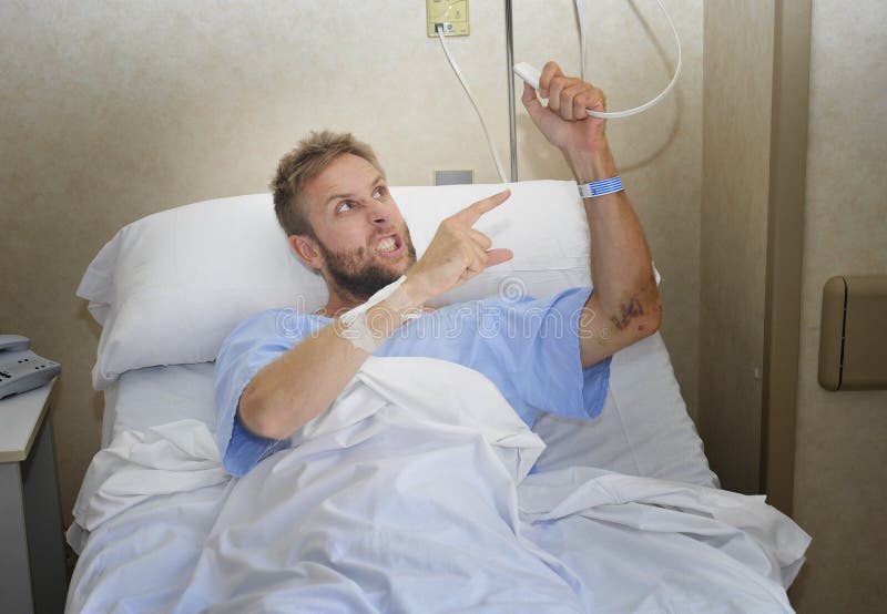 Hombre paciente enojado en el sitio de hospital que miente en la cama que presiona la sensación del botón de la llamada de la enf foto de archivo Hombre paciente enojado en el sitio de hospital que miente en la cama que presiona la sensación del botón de la llamada de la enf foto de archivo