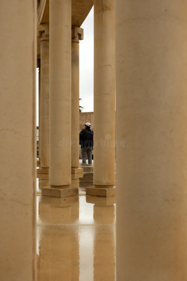 Hombre pasando entre columnas antiguas en un día lluvioso fotografía de archivo libre de regalías