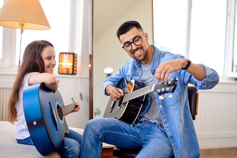 Hombre pasando un momento especial con su pequeña hija cantando y tocando guitarra