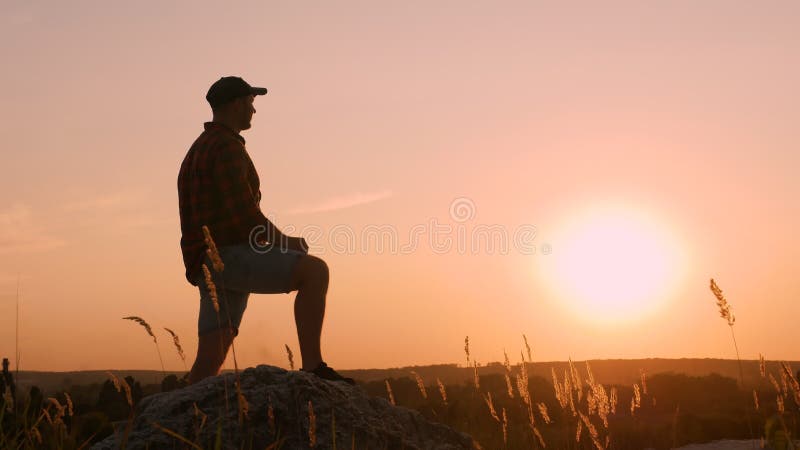 Hombre pensativo sobre una montaña al atardecer. soñador mirando a la distancia joven feliz disfrutando de la puesta de sol en la almacen de metraje de vídeo