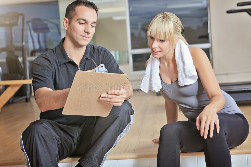 Hombre personal del instructor de la mujer del gimnasio con el equipo de entrenamiento del peso imagen de archivo libre de regalías Hombre personal del instructor de la mujer del gimnasio con el equipo de entrenamiento del peso imagen de archivo libre de regalías