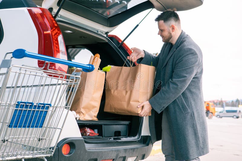 Hombre poniendo bolsas con producto en el maletero del coche espacio de  copia