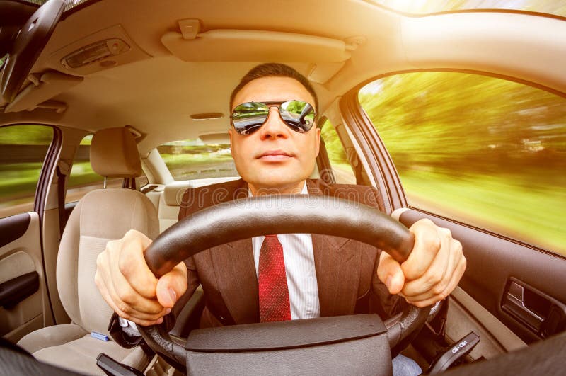 Man in a suit and sunglasses driving on a road in the car. Man in a suit and sunglasses driving on a road in the car.