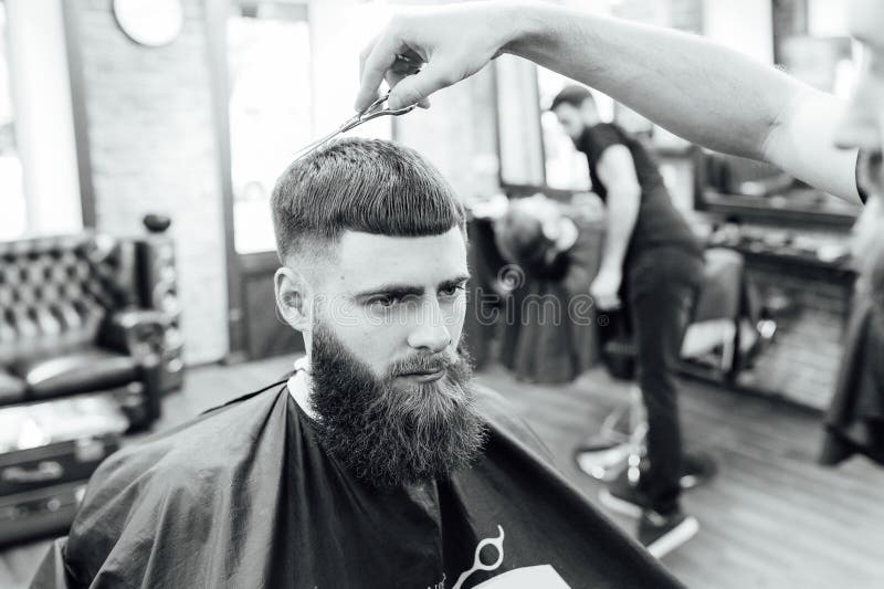 Hombre que consigue corte de pelo de moda en la peluquería de caballeros foto de archivo Hombre que consigue corte de pelo de moda en la peluquería de caballeros foto de archivo