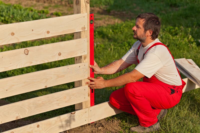 Hombre que construye la cerca de madera fotografía de archivo libre de regalías Hombre que construye la cerca de madera fotografía de archivo libre de regalías