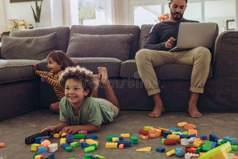 Hombre que cuida a niños a sus niños y que trabaja de hogar fotos de archivo