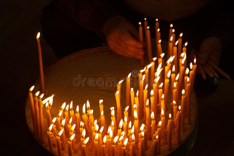 Hombre que enciende velas en una iglesia foto de archivo Hombre que enciende velas en una iglesia foto de archivo