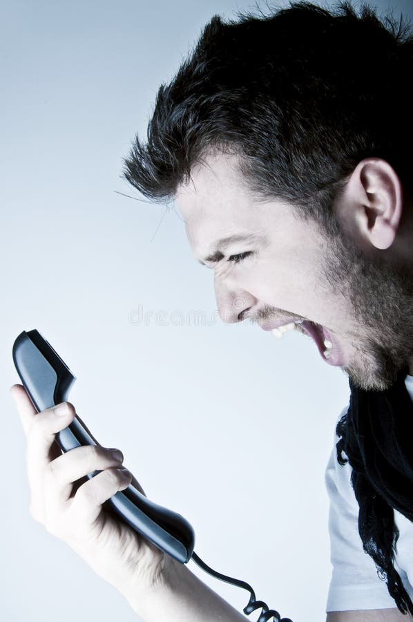 Angry young man shouting on the wired telephone. Angry young man shouting on the wired telephone