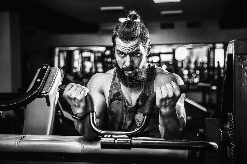 Hombre que hace el ejercicio pesado para el bíceps en la máquina en un gimnasio imagen de archivo libre de regalías Hombre que hace el ejercicio pesado para el bíceps en la máquina en un gimnasio imagen de archivo libre de regalías