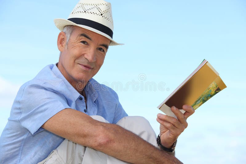 Hombre que lee un libro afuera