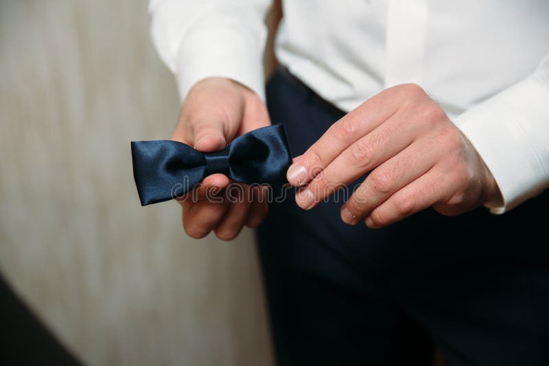 Hombre que lleva a cabo la corbata de lazo negra en sus manos Clother elegante del caballero Concepto de vestido del negocio foto de archivo libre de regalías Hombre que lleva a cabo la corbata de lazo negra en sus manos Clother elegante del caballero Concepto de vestido del negocio foto de archivo libre de regalías