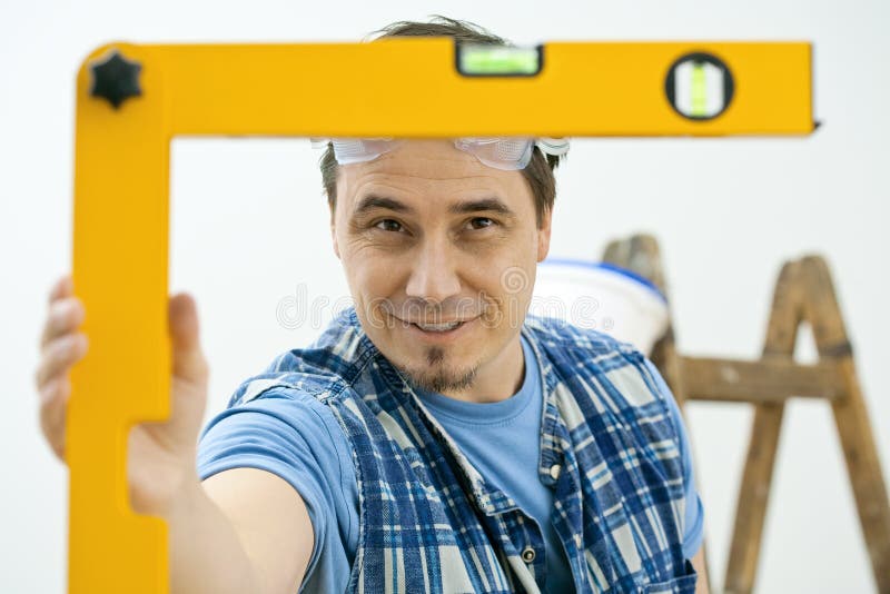 Man improving home, using square level tool, focusing on the bubble. Isolated on white background. Man improving home, using square level tool, focusing on the bubble. Isolated on white background.