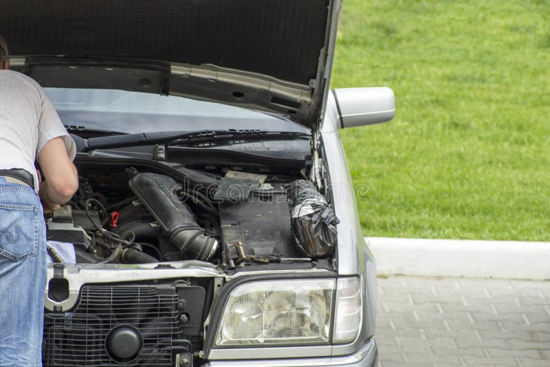 hombre que mira el motor de coche analizado por el lado del camino foto de archivo hombre que mira el motor de coche analizado por el lado del camino foto de archivo