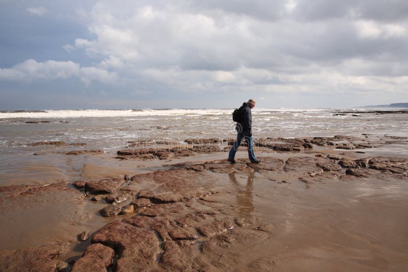 Hombre que recorre a lo largo de la playa de Scarborough imagen de archivo Hombre que recorre a lo largo de la playa de Scarborough imagen de archivo
