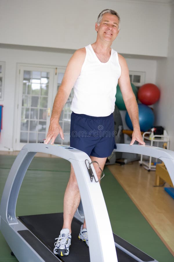 Hombre que se ejecuta en la rueda de ardilla en la gimnasia imagenes de archivo Hombre que se ejecuta en la rueda de ardilla en la gimnasia imagenes de archivo