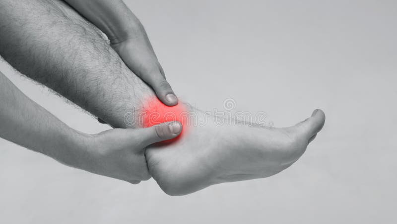 Hombre que se sostiene el tobillo en dolor, foto monocromática imagen de archivo Hombre que se sostiene el tobillo en dolor, foto monocromática imagen de archivo