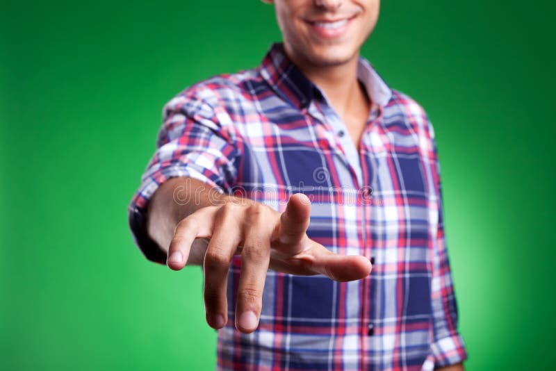 Cropped picture of a young man pointing to the camera or pushing animaginary button, on green background. Cropped picture of a young man pointing to the camera or pushing animaginary button, on green background