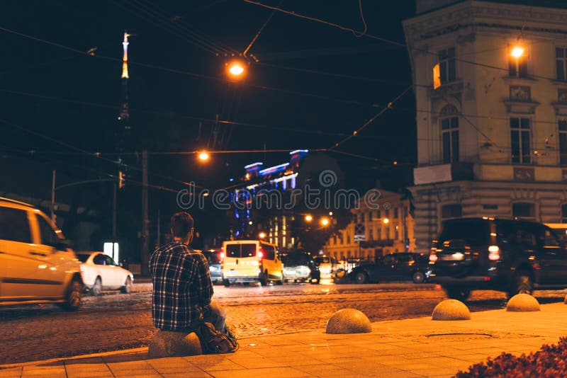 Hombre que sienta y que mira la ciudad de la noche fotos de archivo Hombre que sienta y que mira la ciudad de la noche fotos de archivo