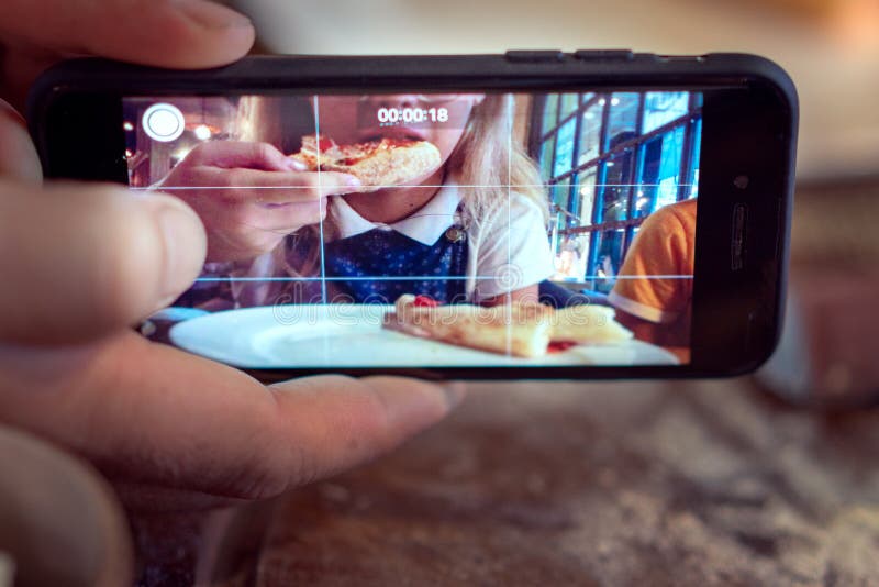 Hombre que toma la foto de una muchacha que come la pizza fotos de archivo libres de regalías Hombre que toma la foto de una muchacha que come la pizza fotos de archivo libres de regalías