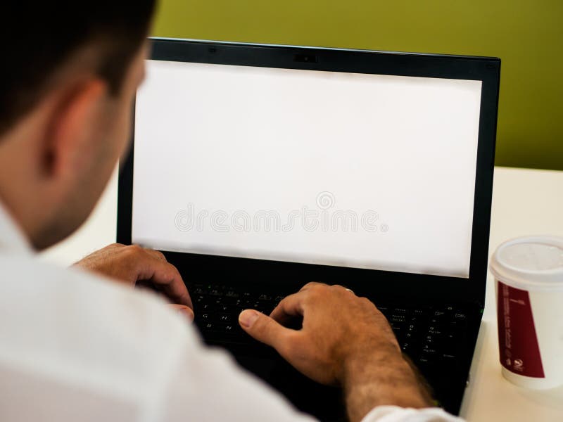 Hombre que usa el ordenador portátil con la pantalla en blanco en el escritorio imagen de archivo Hombre que usa el ordenador portátil con la pantalla en blanco en el escritorio imagen de archivo