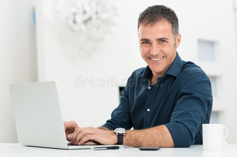 Hombre que usa el ordenador portátil en el escritorio