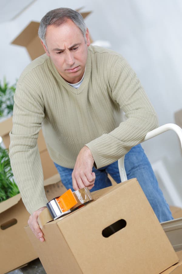 Hombre que utiliza cinta adhesiva en la caja de cartón fotografía de archivo libre de regalías