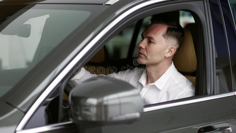 Hombre sentado dentro de un vehículo en el concesionario de coches almacen de video