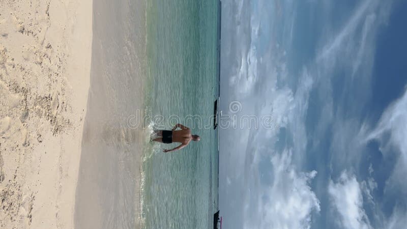 Hombre sin camisa caminando hacia el mar para nadar durante el verano