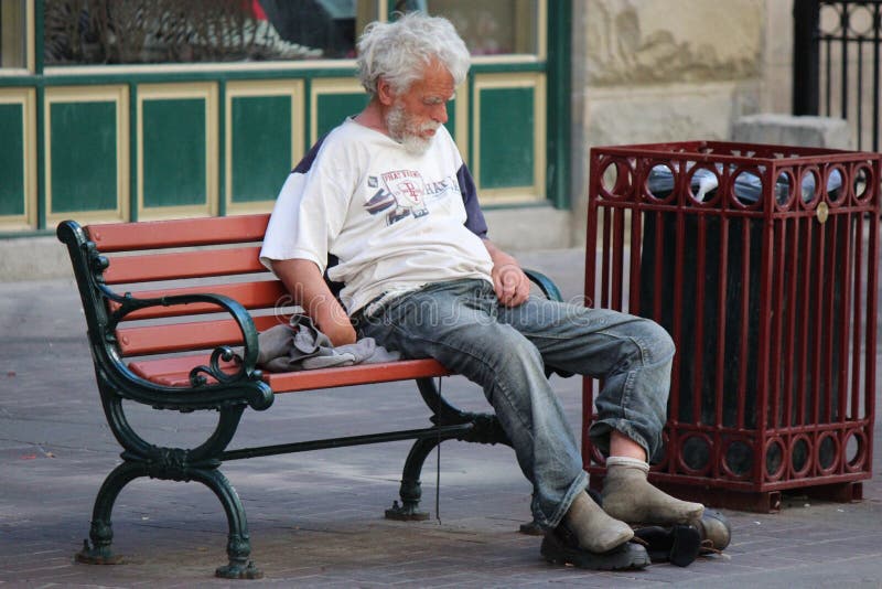 Hombre sin hogar que se sienta en un banco de parque en Stephen Avenue en Calgary Alberta imagen de archivo libre de regalías Hombre sin hogar que se sienta en un banco de parque en Stephen Avenue en Calgary Alberta imagen de archivo libre de regalías