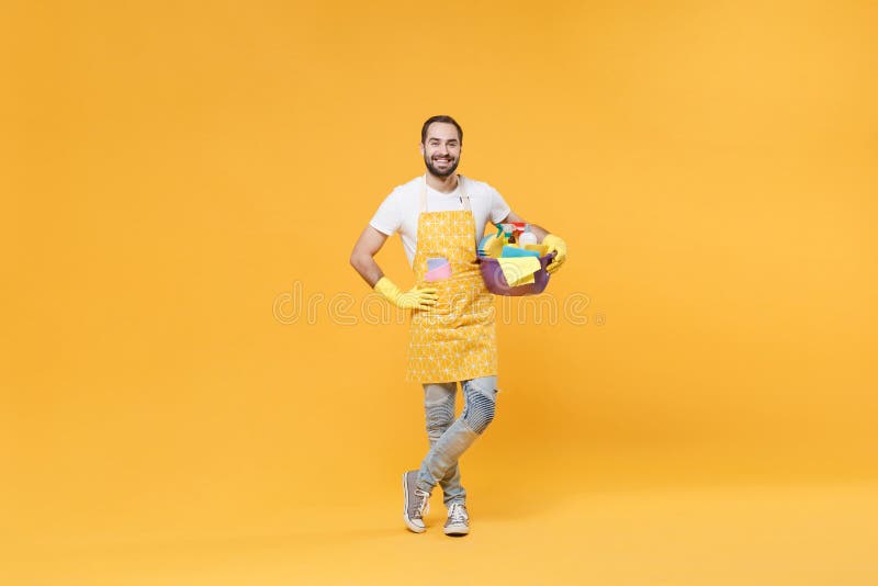 Hombre sonriente ama de casa en guantes de goma de manzana sostienen botellas detergentes lavadoras de cuencas haciendo trabajo de fotos de archivo