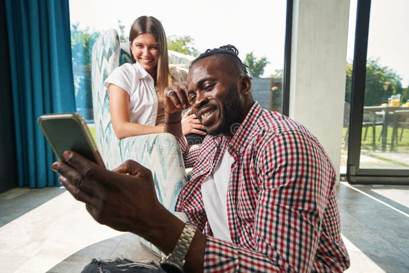 Hombre sonriente con smartphone y mujer alegre foto de archivo
