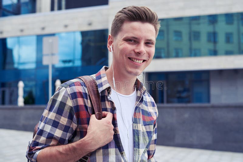 Hombre sonriente que mira la cámara mientras que camina en el centro de la ciudad con fotografía de archivo Hombre sonriente que mira la cámara mientras que camina en el centro de la ciudad con fotografía de archivo