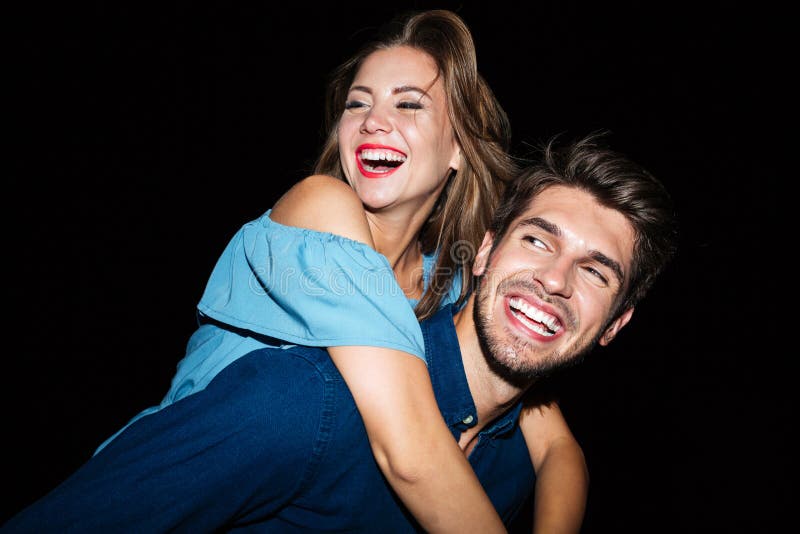 Hombre sonriente que retiene a la novia en el suyo en la noche imagen de archivo Hombre sonriente que retiene a la novia en el suyo en la noche imagen de archivo
