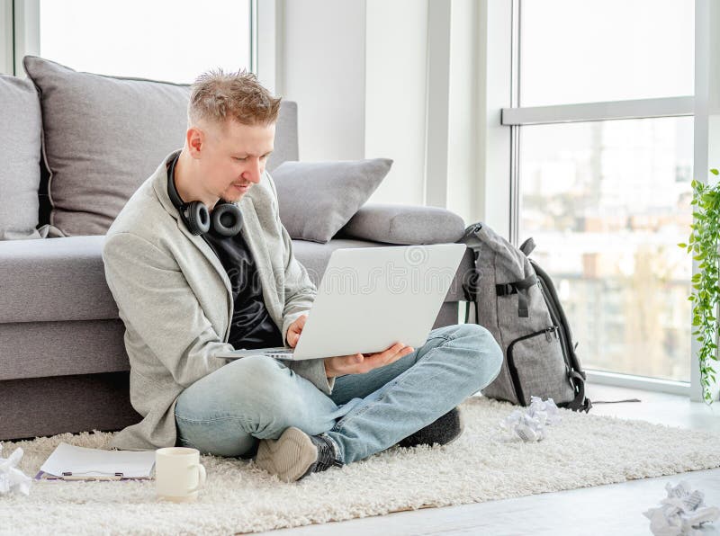 Smiling man working on laptop and phone at home. Smiling man working on laptop and phone at home