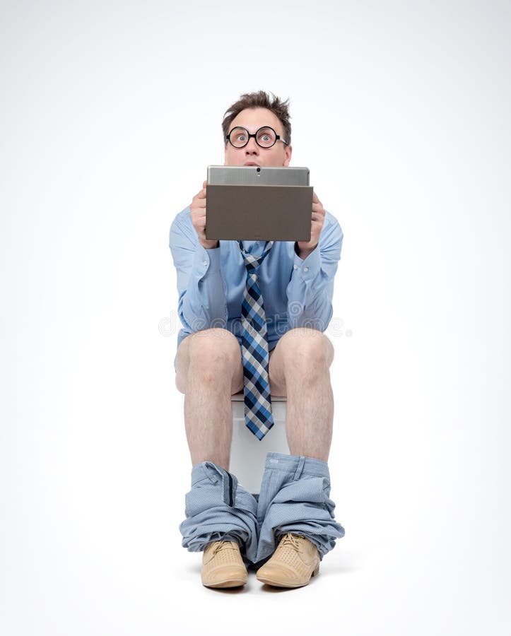 Hombre sorprendido en vidrios, con la PC de la tableta sentándose en el retrete, en fondo ligero Concepto de situación fotos de archivo Hombre sorprendido en vidrios, con la PC de la tableta sentándose en el retrete, en fondo ligero Concepto de situación fotos de archivo