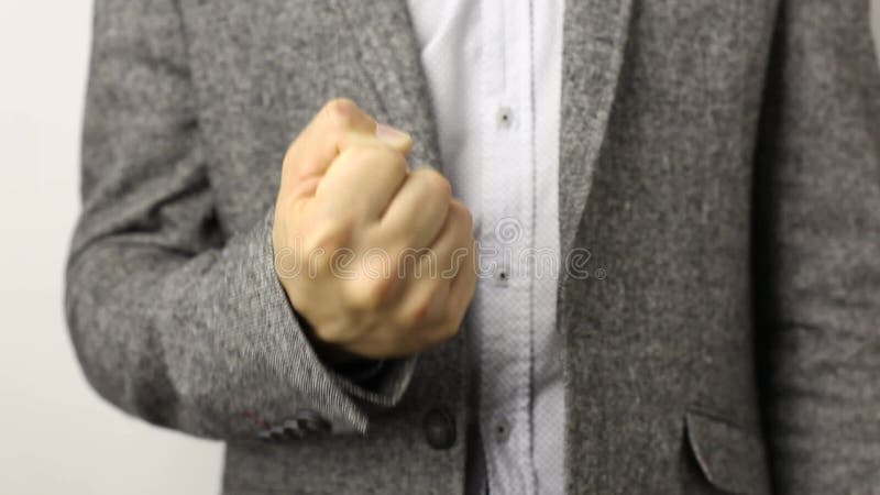 Hombre sólido con chaqueta gris sobre fondo blanco tirando de puño hacia arriba. concepto de gesto de amenaza de agresión castigo metrajes
