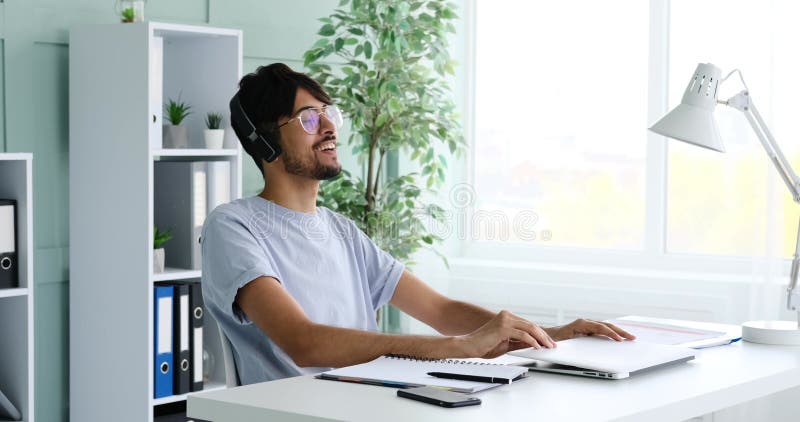 Hombre terminando el trabajo en laptop y escuchando música en auriculares