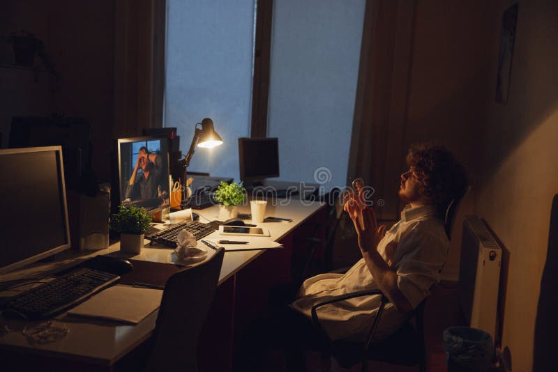 Hombre trabajando solo en el cargo durante la cuarentena del coronavirus o del COVID-19, permaneciendo hasta tarde en la noche fotografía de archivo Hombre trabajando solo en el cargo durante la cuarentena del coronavirus o del COVID-19, permaneciendo hasta tarde en la noche fotografía de archivo