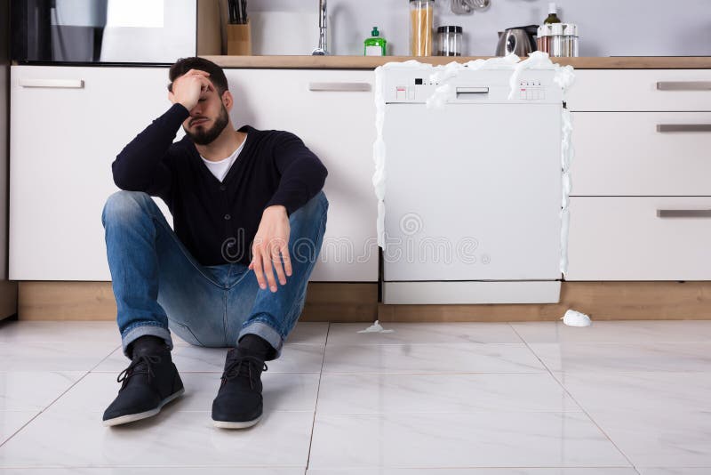 Hombre trastornado que se sienta al lado del lavaplatos imagen de archivo Hombre trastornado que se sienta al lado del lavaplatos imagen de archivo