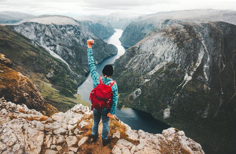 Hombre valiente que viaja en las montañas de Noruega que se colocan en el acantilado imagenes de archivo